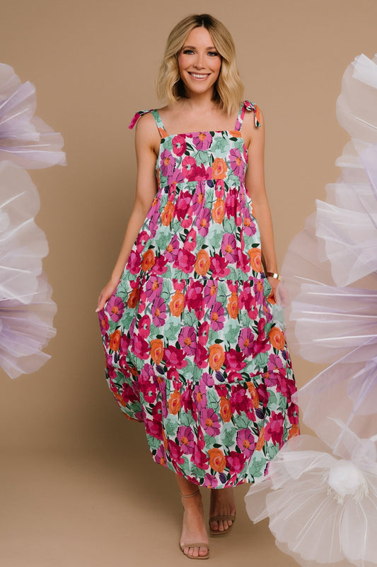 Front view of Lakewood Tie Dress in pink, orange, and green floral print showing square neckline, adjustable bow straps, and tiered midi skirt.