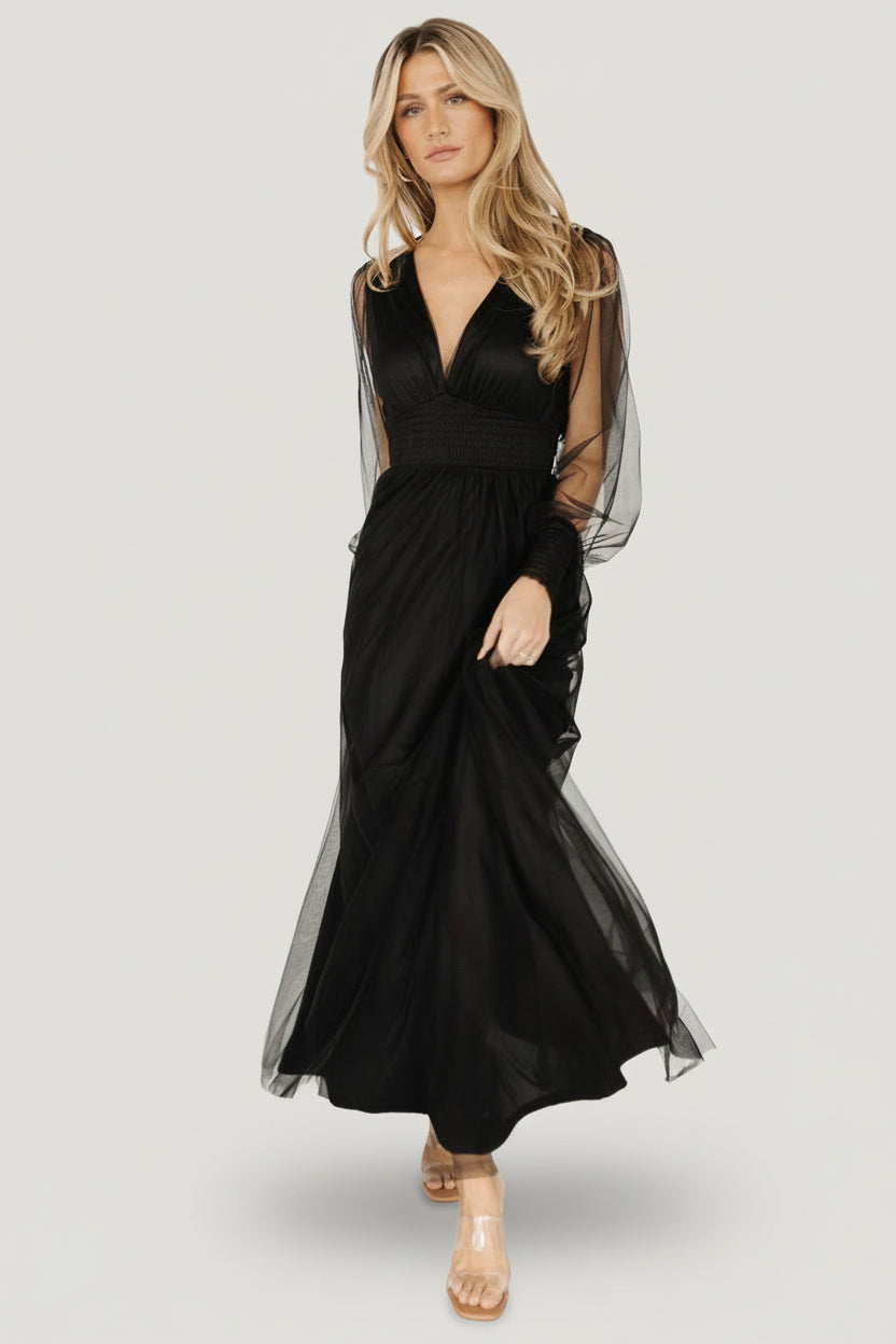 Three-quarter view of black Layla Tulle Maxi Dress highlighting the smocked waist, flowing layered skirt, and sheer long sleeves with smocked cuffs.