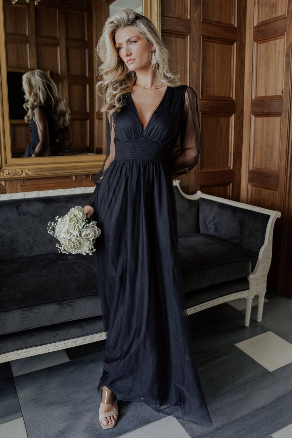 Front view of Layla Tulle Maxi Dress in black showing deep V-neck, smocked waist, long smocked sleeves, and layered tulle skirt in motion.