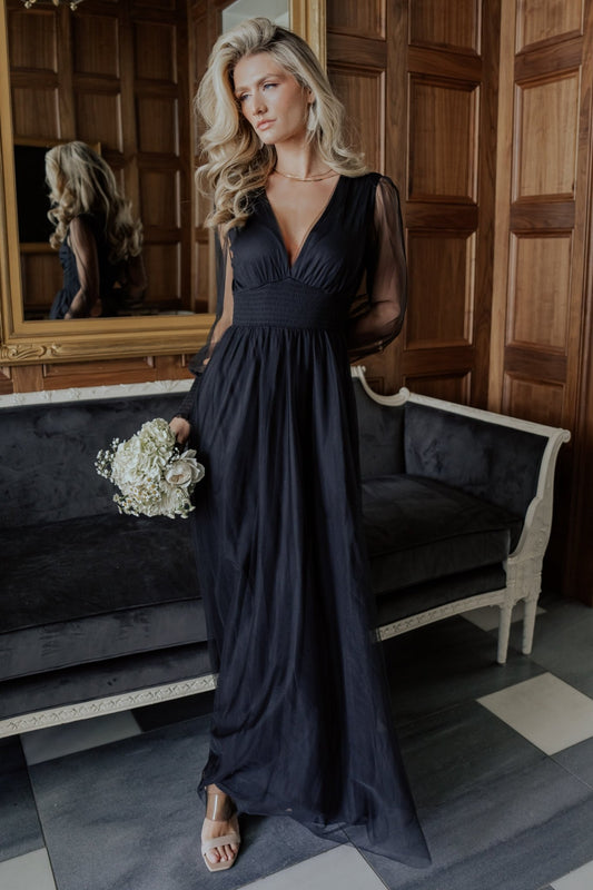 Front view of Layla Tulle Maxi Dress in black showing deep V-neck, smocked waist, long smocked sleeves, and layered tulle skirt in motion.