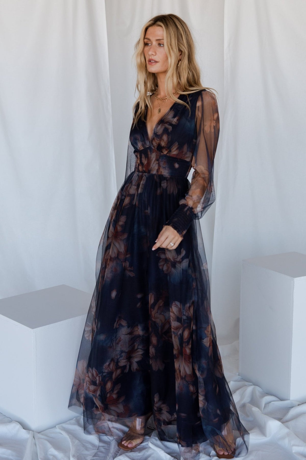 Back view of dark blue floral tulle maxi dress showing flowing skirt and delicate floral print across the bodice.