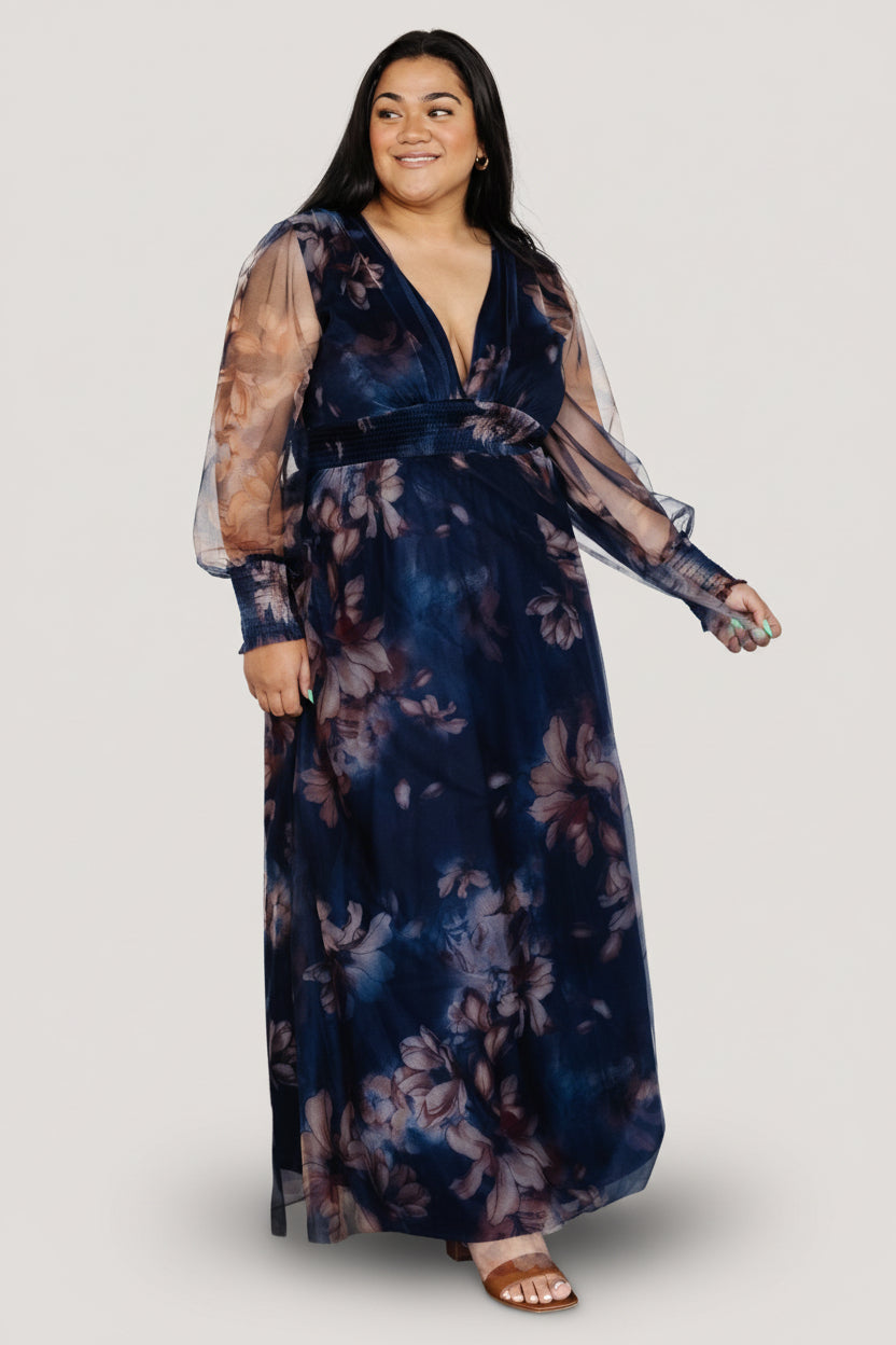 Close-up of deep V-neck and smocked waist on dark blue floral tulle maxi dress, highlighting fabric texture and print.