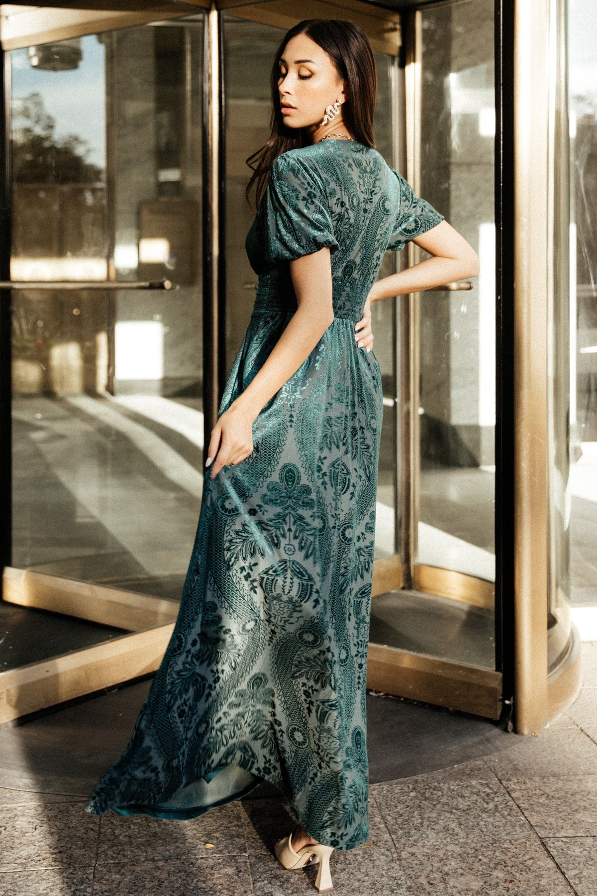 Side profile of the emerald velvet maxi dress illustrating skirt drape, ankle-length hem, and discreet side pocket placement.