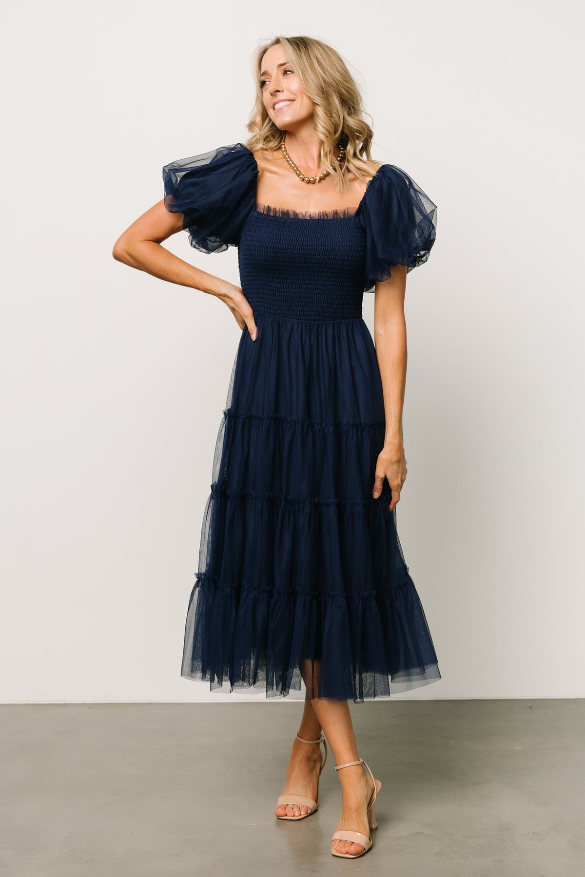 Front view of the navy Liv tulle midi dress on model, showing smocked bodice, ruffle square neckline and tiered skirt in motion.
