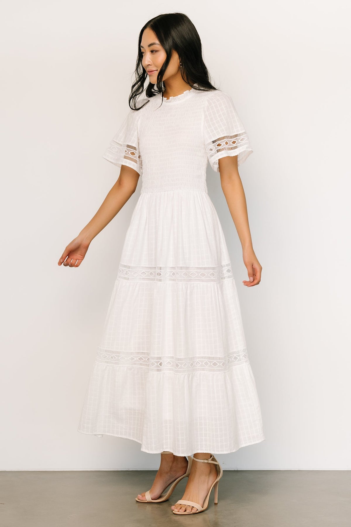 Full-length side profile of Loveland Geo Lace Maxi Dress in off-white, highlighting elastic waist, pockets and tiered skirt.
