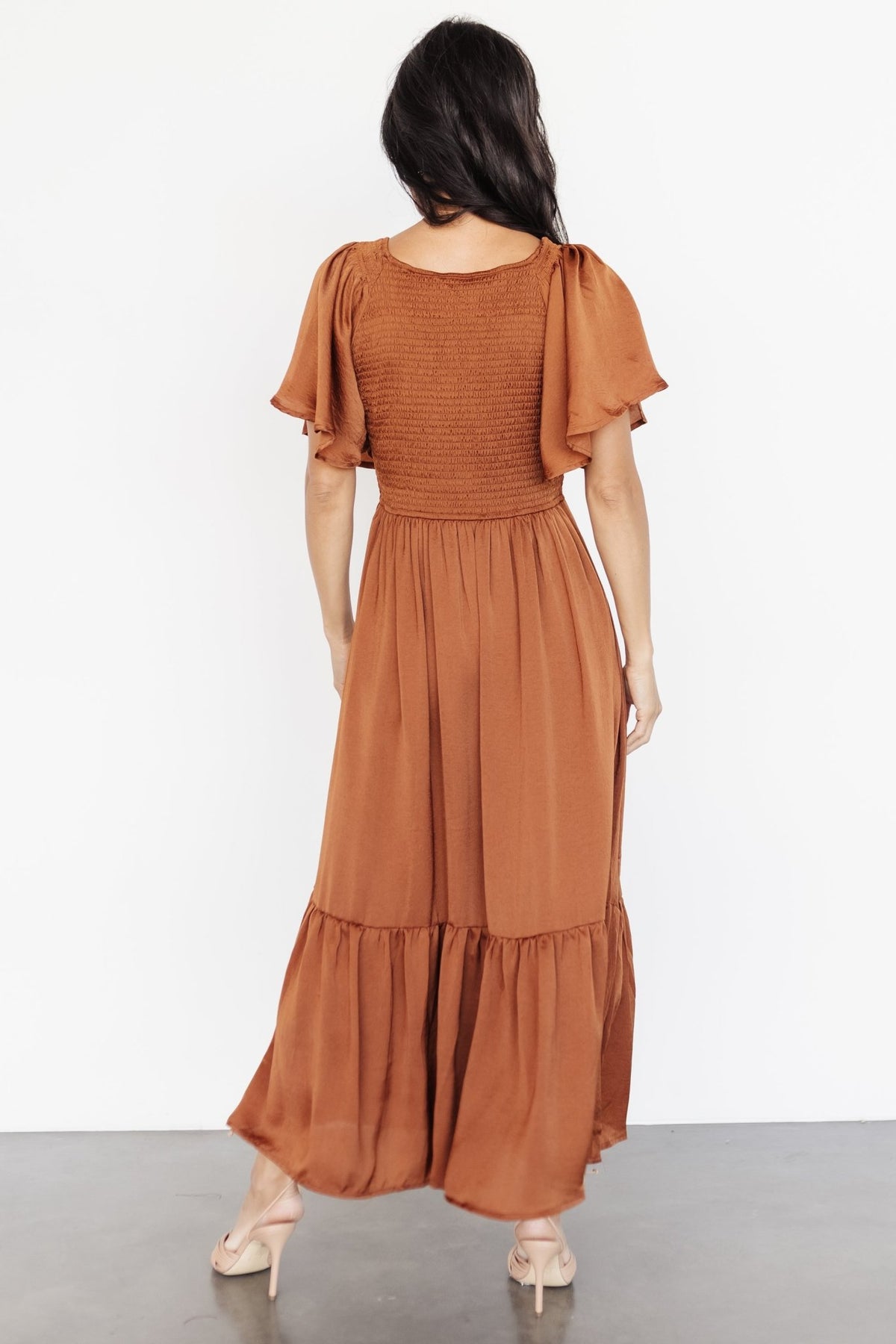Model twirling in dark copper midi dress to show skirt fullness, semi-pleated ruffle detail, and fabric sheen.