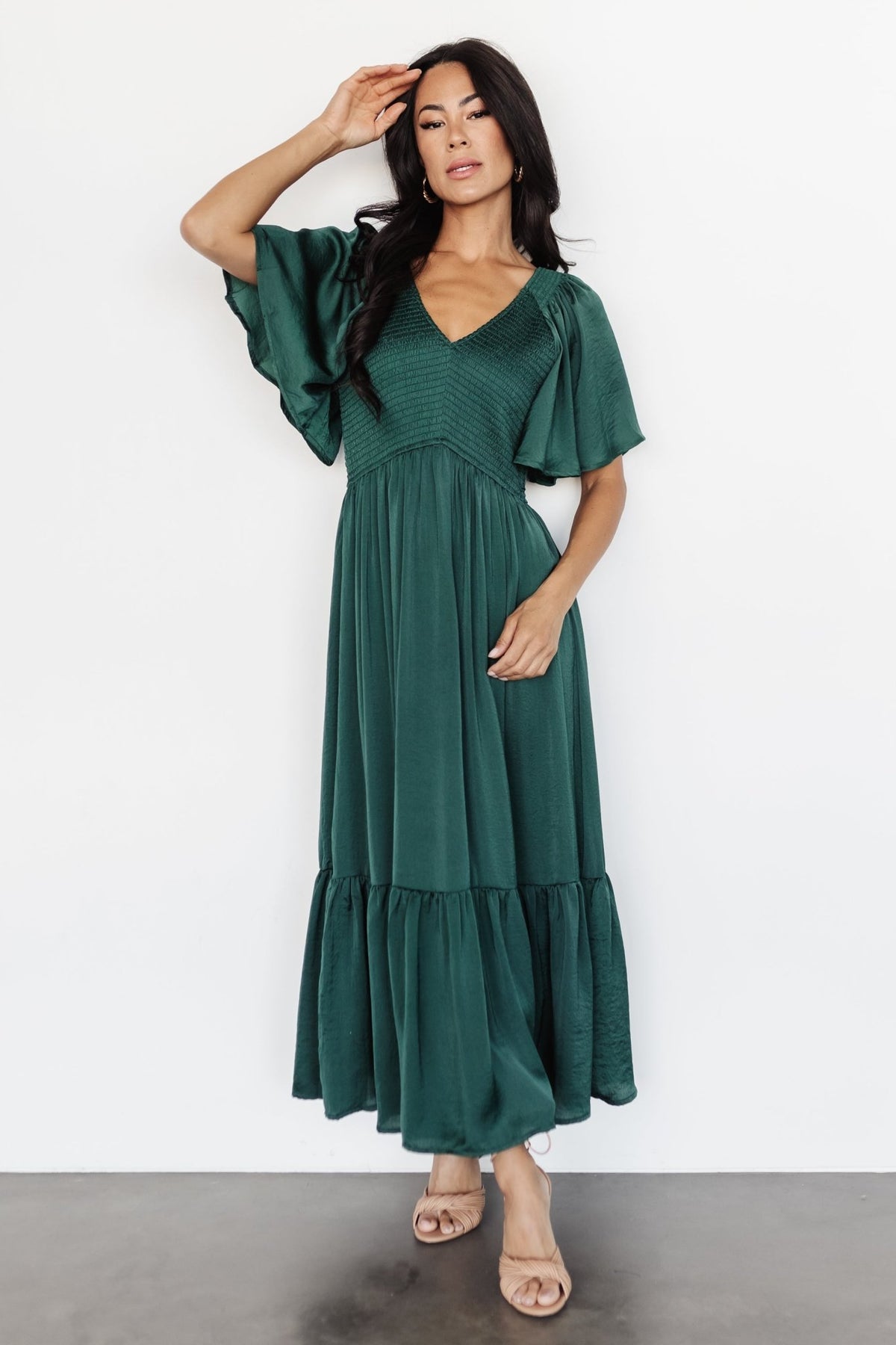 Front view of Lovell Smocked Midi Dress in emerald—smocked bodice, flutter sleeves, ruffle hem, lined skirt.