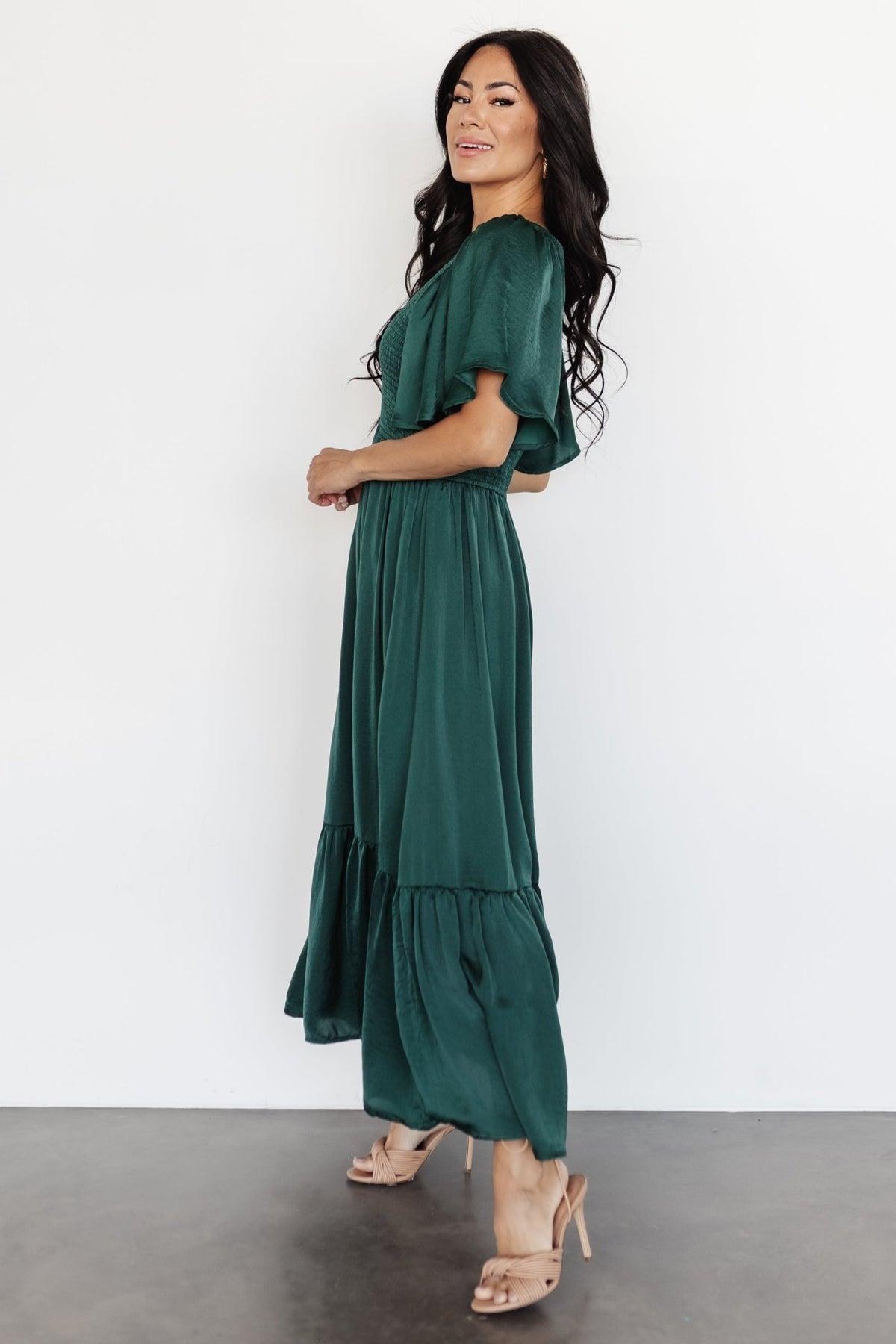 Detail of semi-pleated ruffle hem on Lovell Smocked Midi Dress in emerald showing texture and drape.