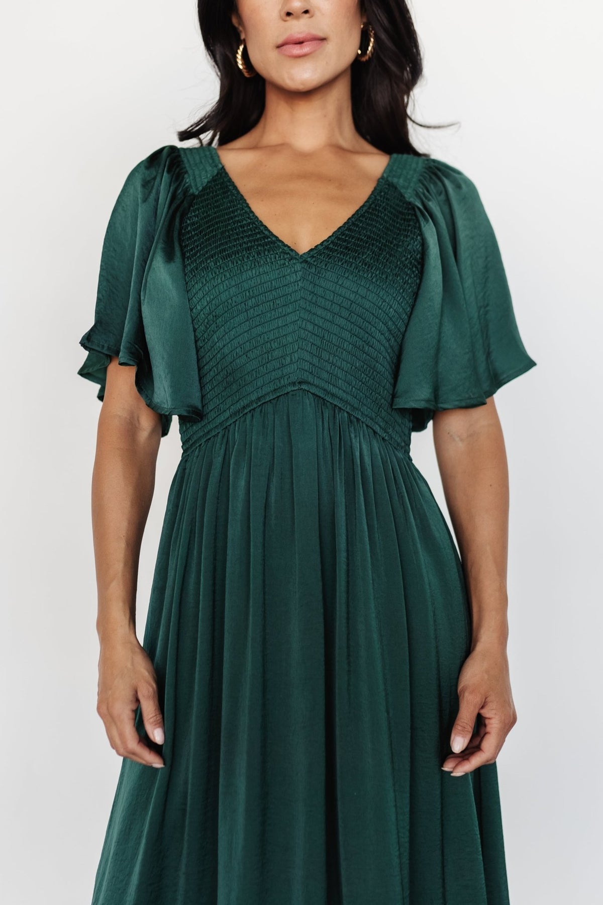 Side view of Lovell Smocked Midi Dress in emerald highlighting flutter sleeves and lined skirt movement.