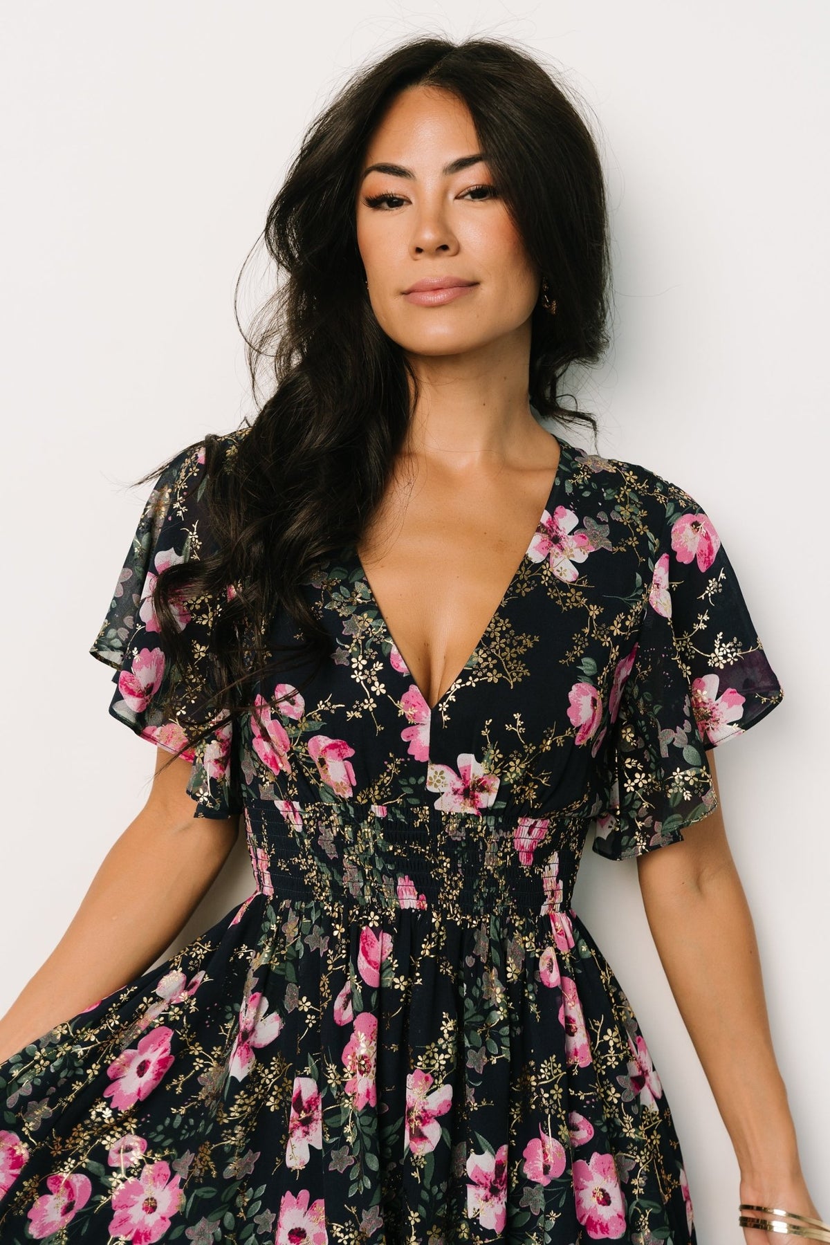 Back and movement view of the Lynlee metallic maxi dress in dark blue with pink print, showing the full skirt and delicate metallic sheen in sunlight.