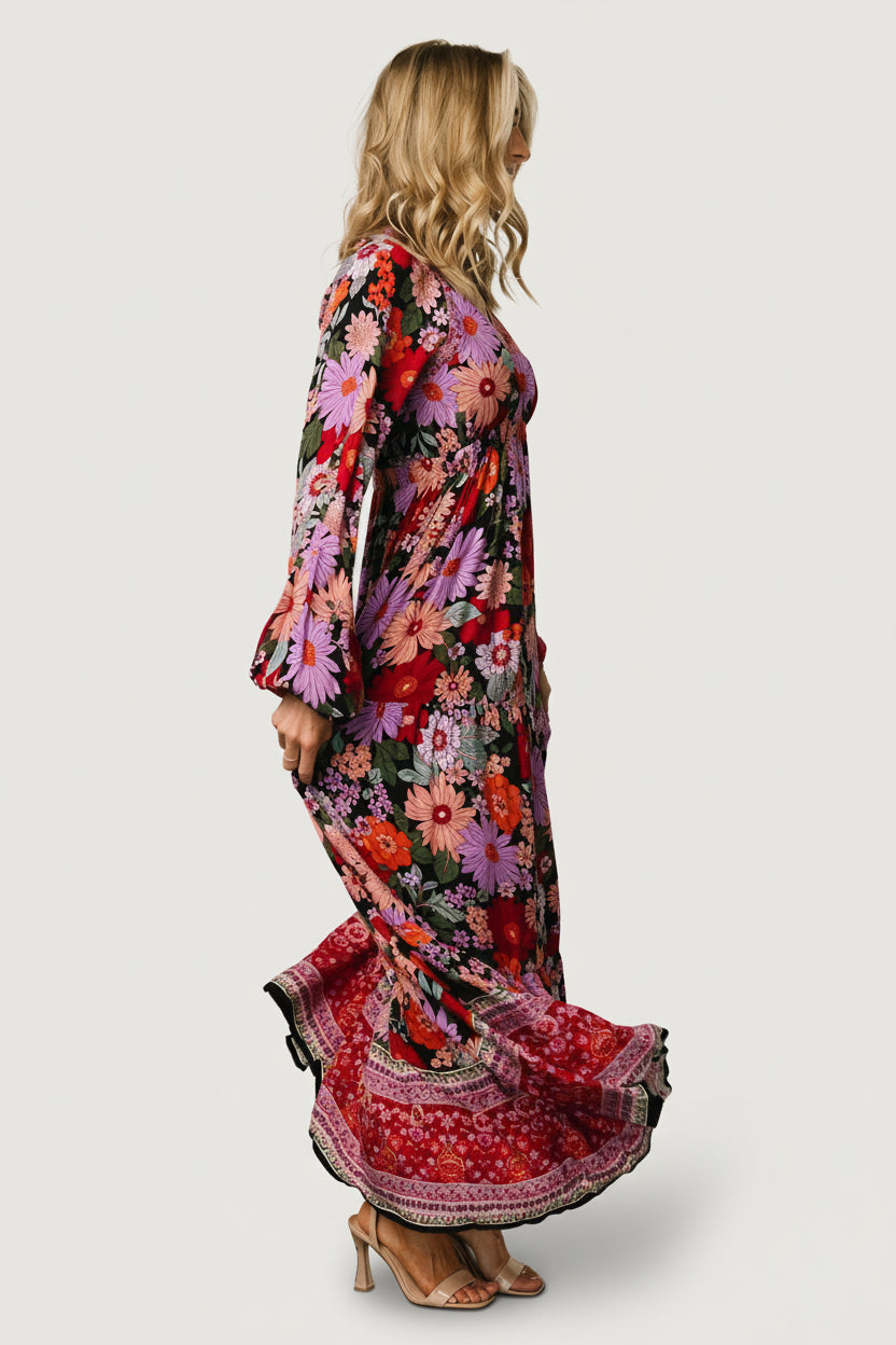 Model walking in Malena Tiered Maxi Dress Black Multi, showing movement of the tiered skirt and left leg slit for ease and style.