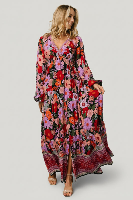Front view of Malena Tiered Maxi Dress in Black Multi floral print on model, showing crossover V-neck, elastic waistband and tiered maxi skirt.