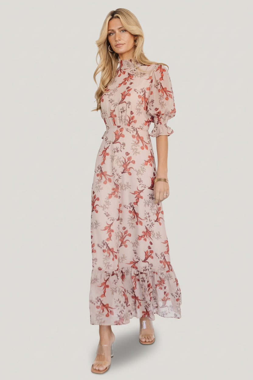 Model walking in blush floral maxi dress to show skirt movement and flow, emphasizing versatile styling for events and daytime wear.