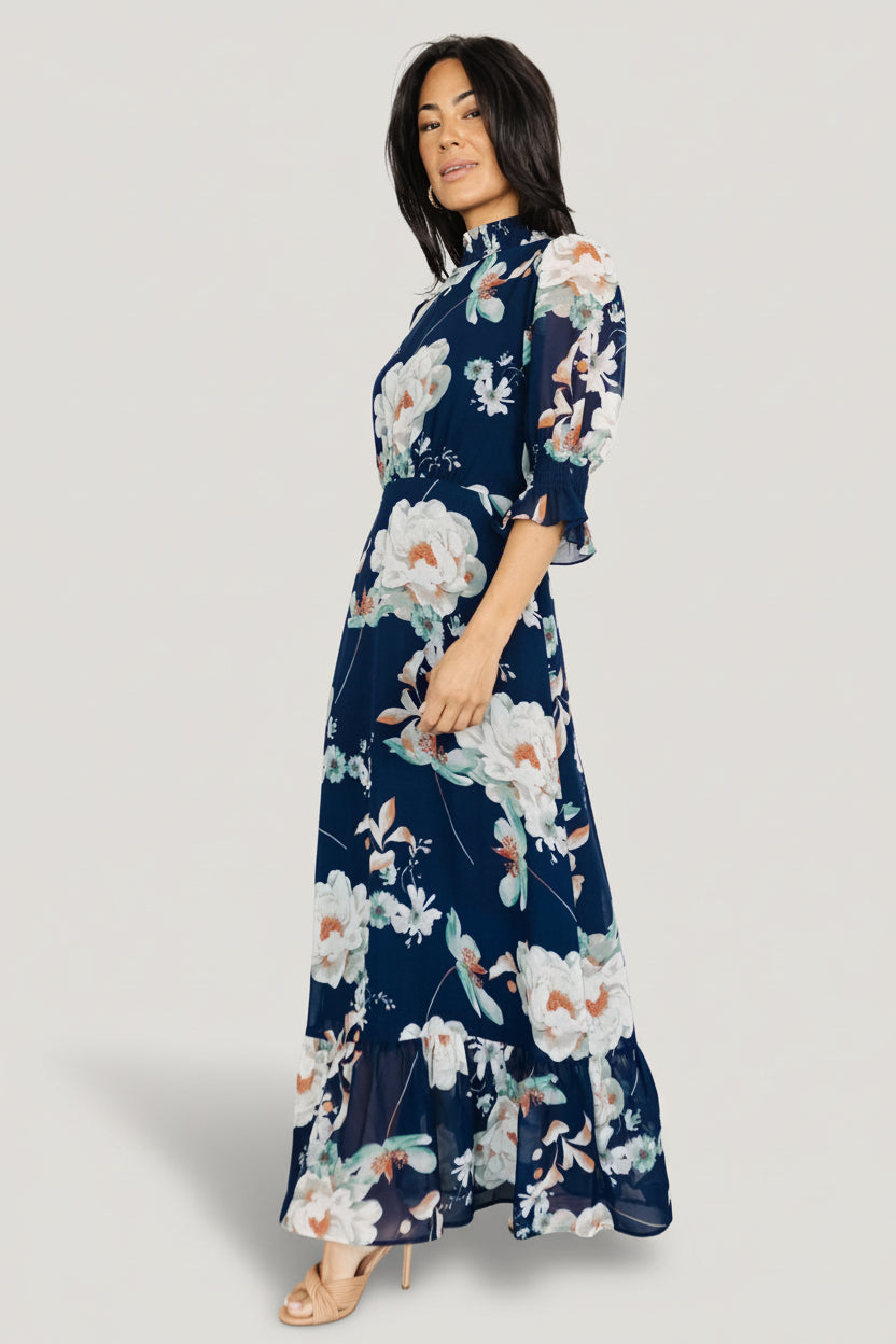 Full-length shot of navy floral maxi dress displaying tiered skirt and feminine floral print with light, airy chiffon drape.