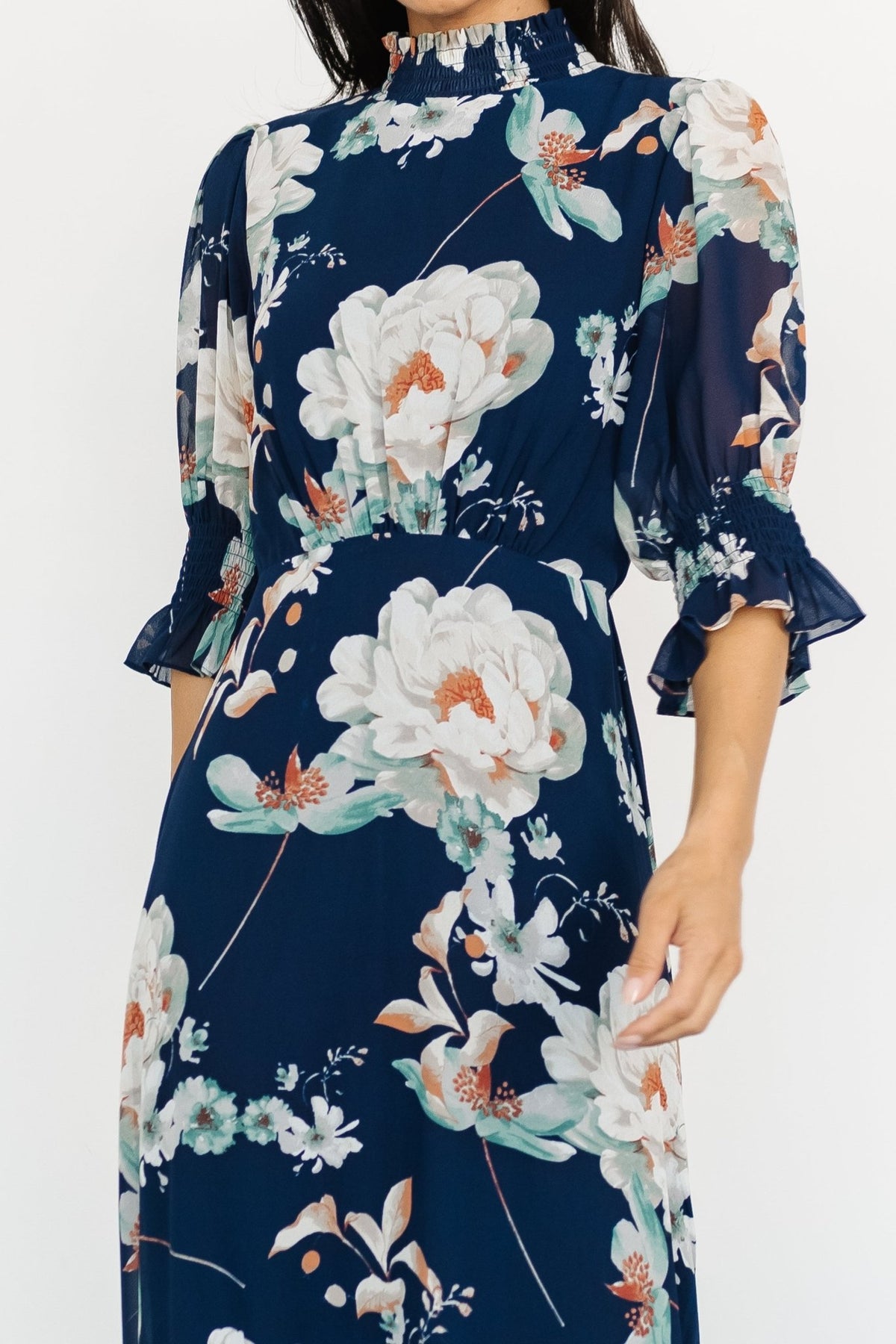 Model wearing navy floral maxi dress with gentle movement captured in the tiered skirt, showing overall silhouette and print scale.