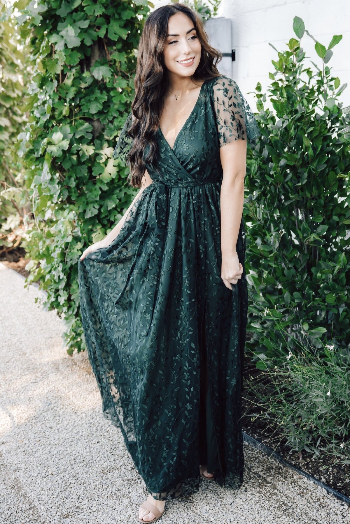 Styled product shot showing elastic waistband with separate self-tie, maxi silhouette, and the vine-embossed texture on dark green organza.