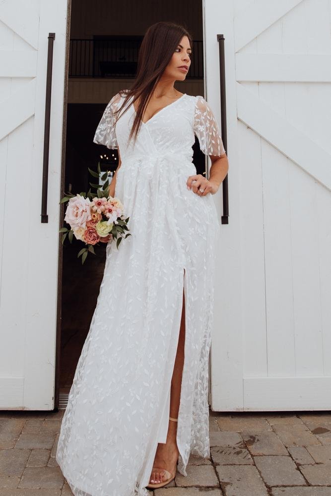 Hanger shot of Marseille vine-embossed organza maxi dress in white, showing full silhouette, left-leg slit, and subtle sheen of the fabric.