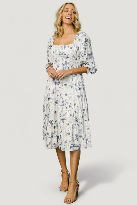 Front view of Marta Smocked Midi Dress in white and blue floral on a model, showing square neckline and tiered skirt.