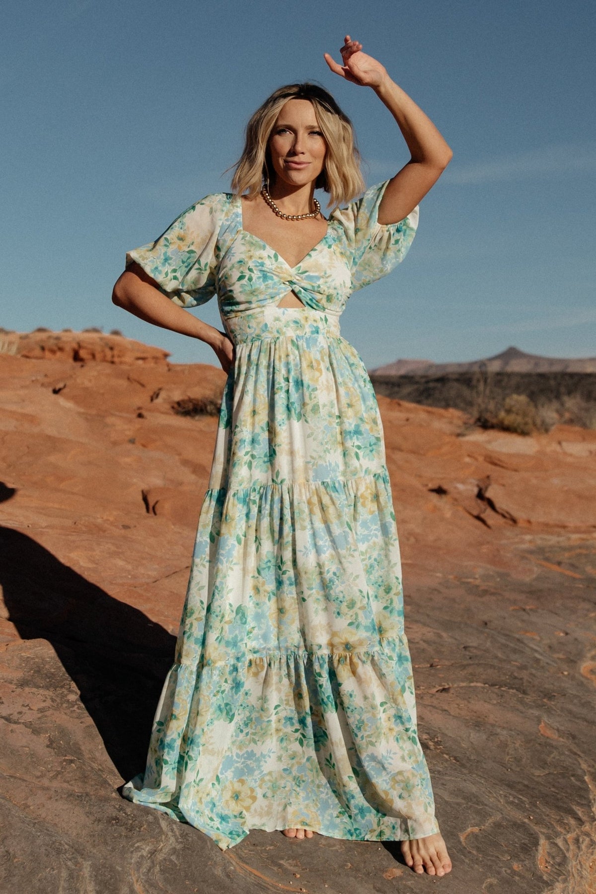 Three-quarter view of Maya Maxi Dress in Garden Multi on model, highlighting elastic shoulders, half sleeves with elastic cuffs, and flowing skirt.