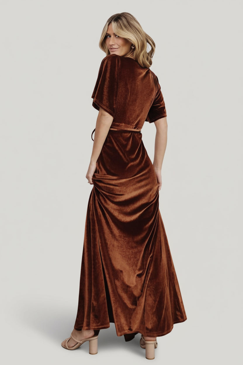 Model wearing Meghan bronze velvet wrap styled for an evening event, highlighting elegant drape, V-neck silhouette and flattering waist tie.