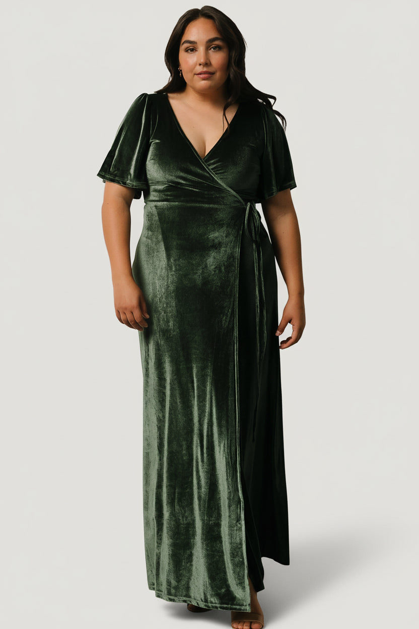 Side profile of the Meghan velvet wrap maxi in deep green, showing sleeve shape, side drape, and tulip hem movement on the model.