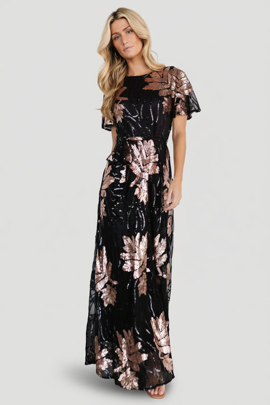 Front view of black maxi dress densely embroidered with rose-gold sequin leaf pattern, round neckline and tied waist sash for shape.