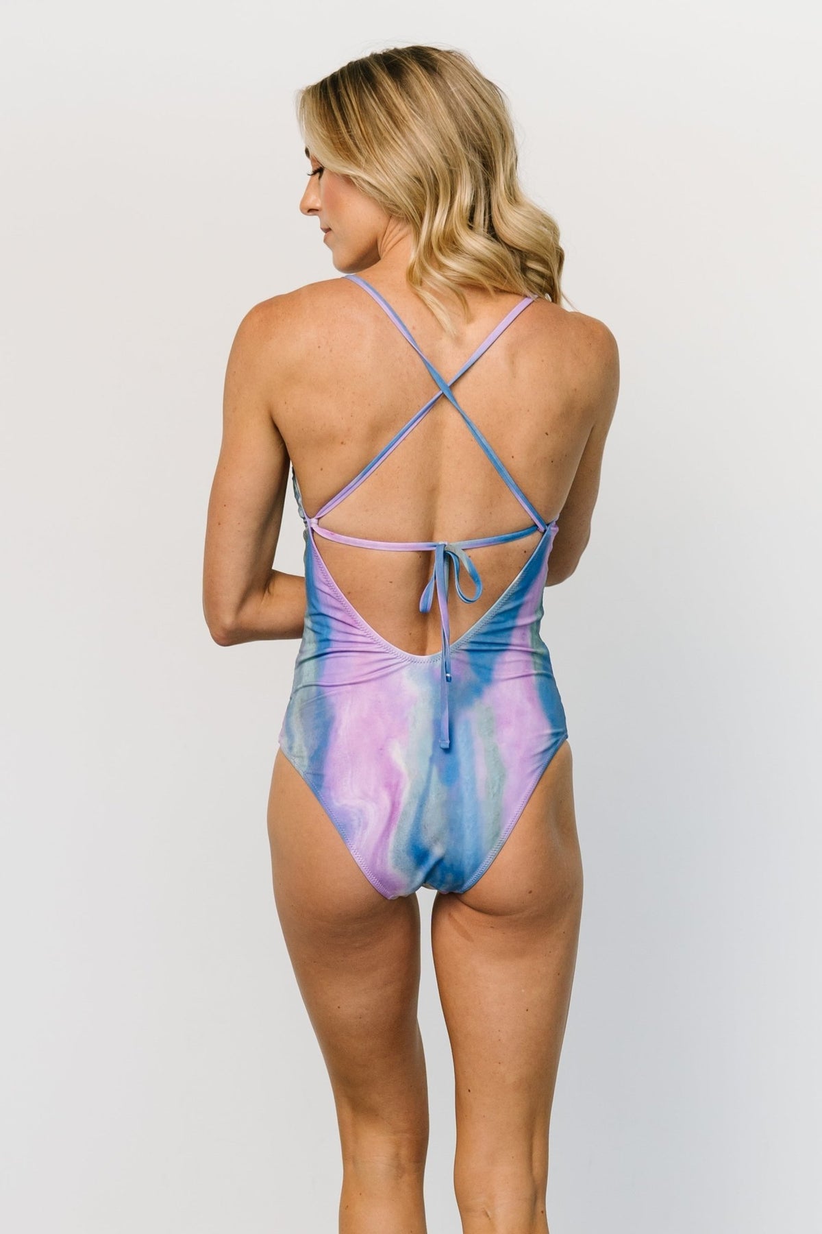 Close-up of tie-dye fabric and seam details on purple-blue one-piece, showing texture and stretch of the nylon-spandex blend.