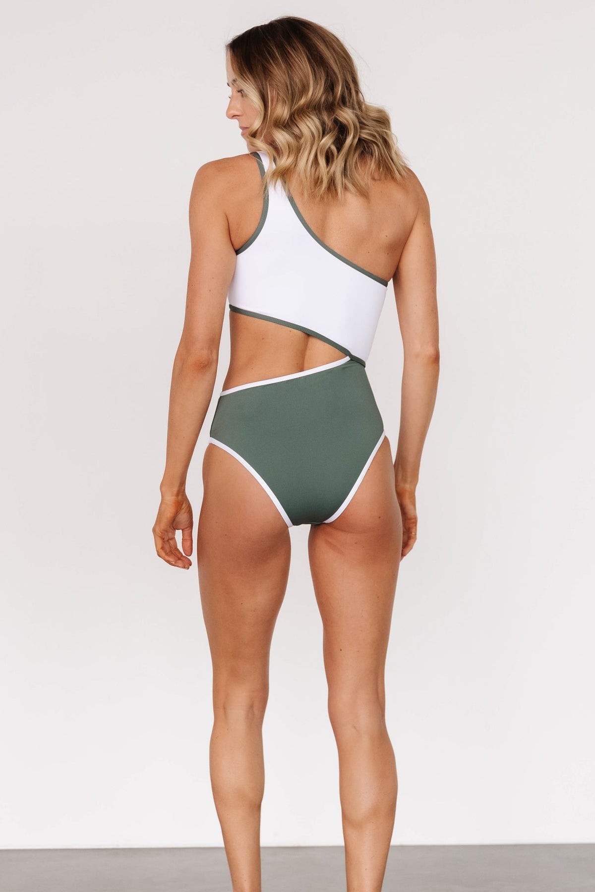 Back and side view of olive-and-white Portofino one-piece showing high-cut leg, asymmetrical cut and moderate coverage.