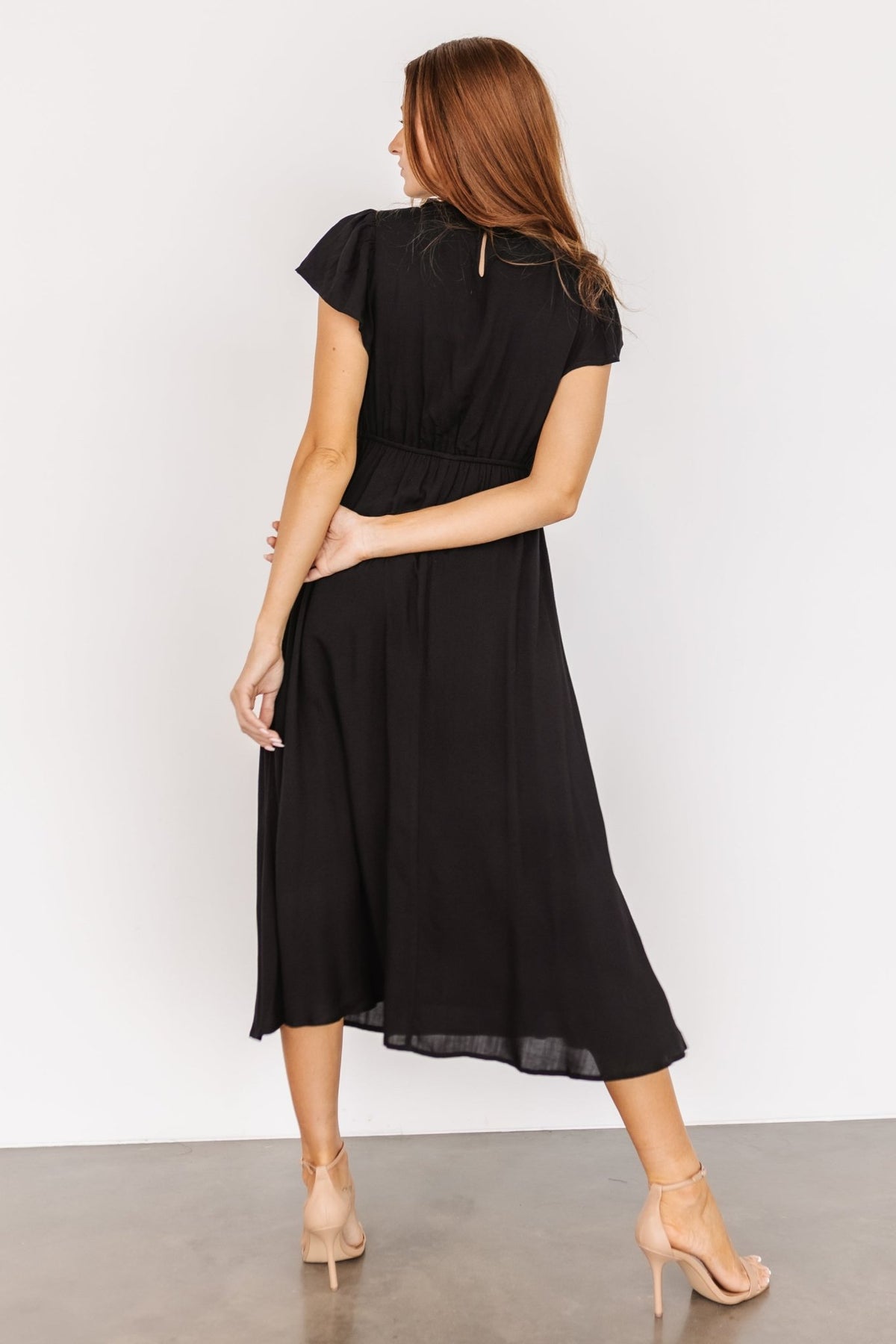 Side view focusing on the practical side pocket and elastic gathering at the waist of the black Prestyn midi dress.