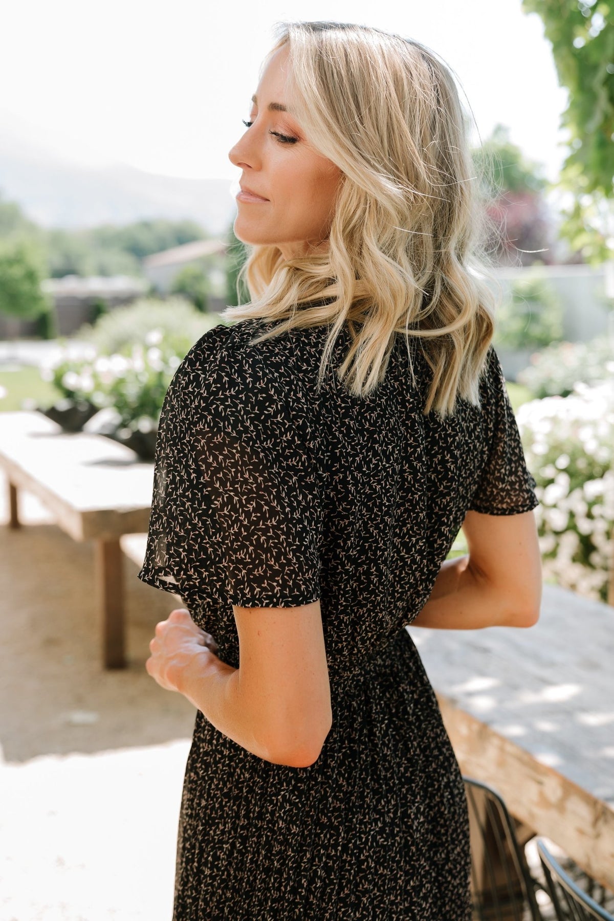 Detail shot of fabric and print on the Prim Pleated Midi Dress: black, taupe and red floral chiffon with fine pleating and soft drape.