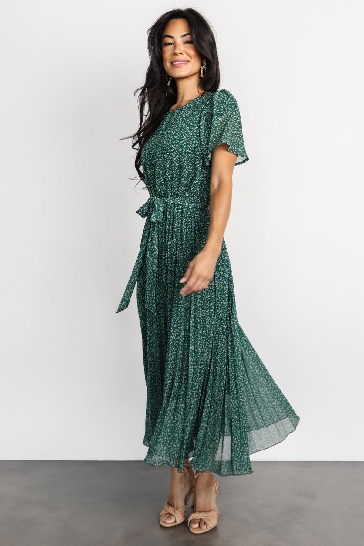 Close-up of green floral chiffon fabric and pleat detail with inner lining visible at the bodice area.
