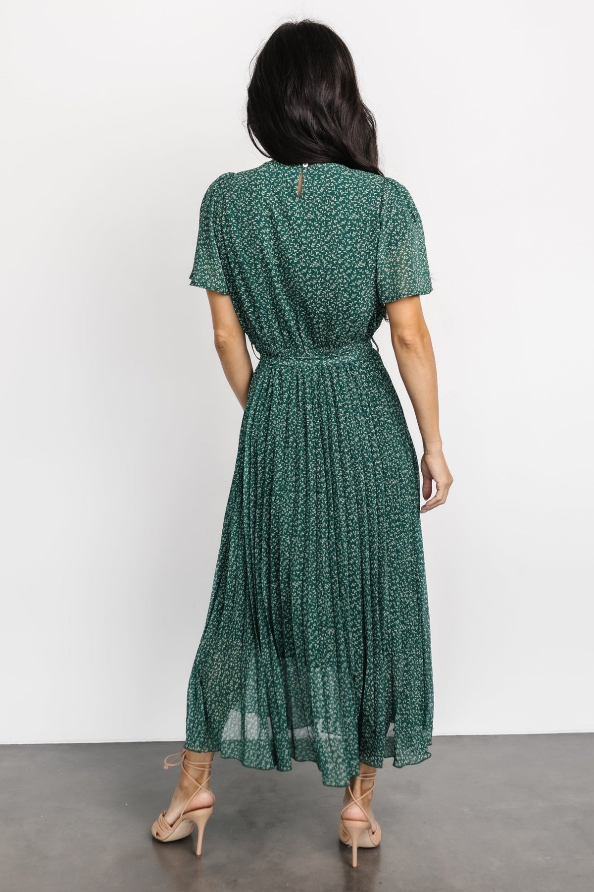 Back view showing button-and-keyhole closure at the neckline and the pleated silhouette of the midi dress.