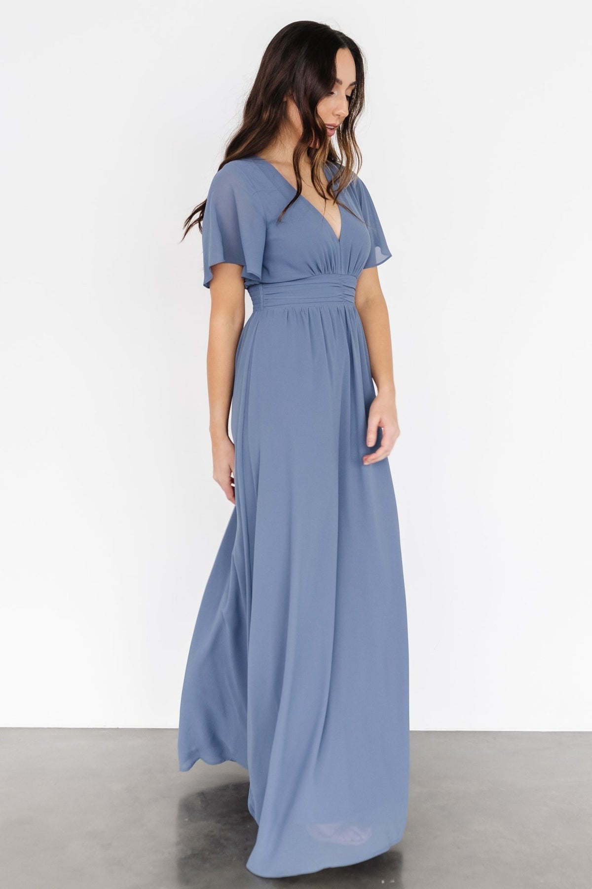 Back view showing smocked back waist for flexible fit, lined skirt and unlined flutter sleeves in soft whisper-blue chiffon.