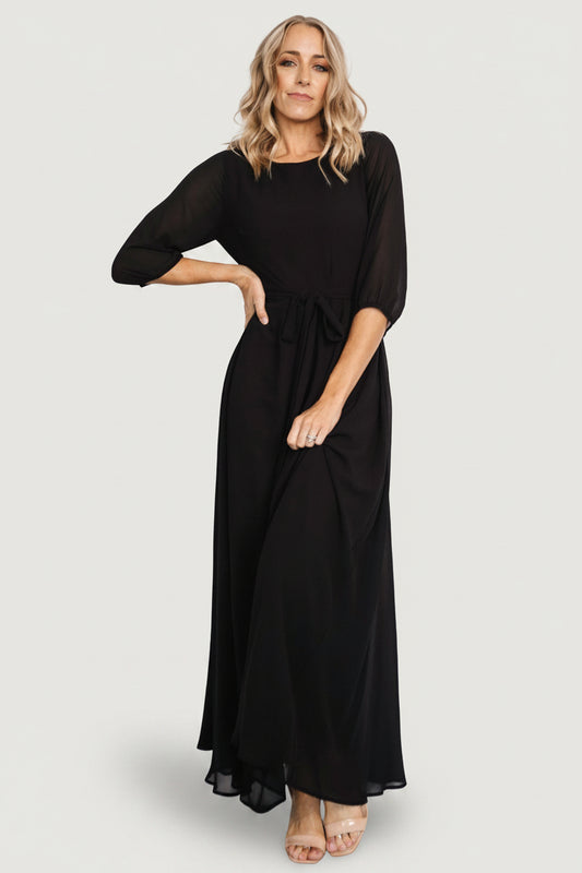 Studio front view of Rebecca Maxi Dress in solid black, highlighting the rounded neckline, removable belt tie and smooth skirt drape.