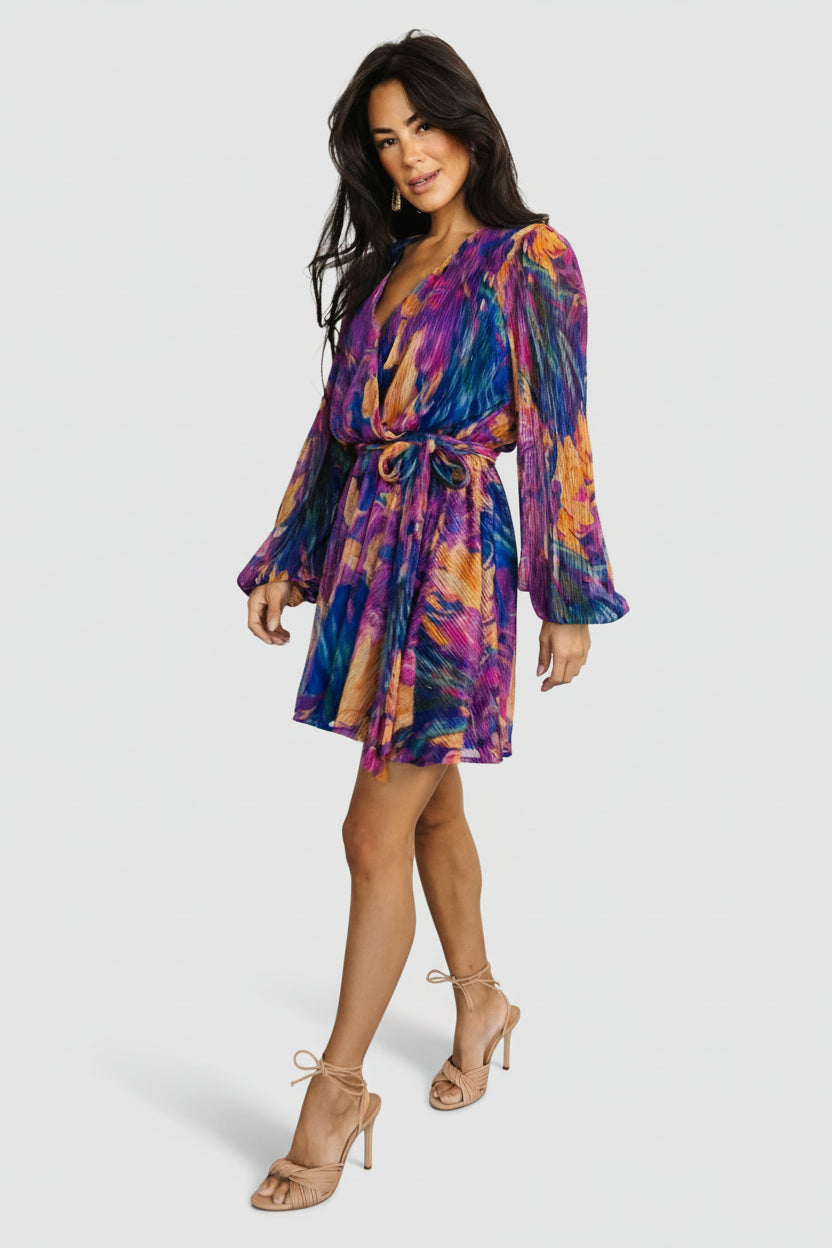 Back view of the Rev mini dress in blue multi print, displaying long sleeves with elastic cuffs and the mini silhouette.