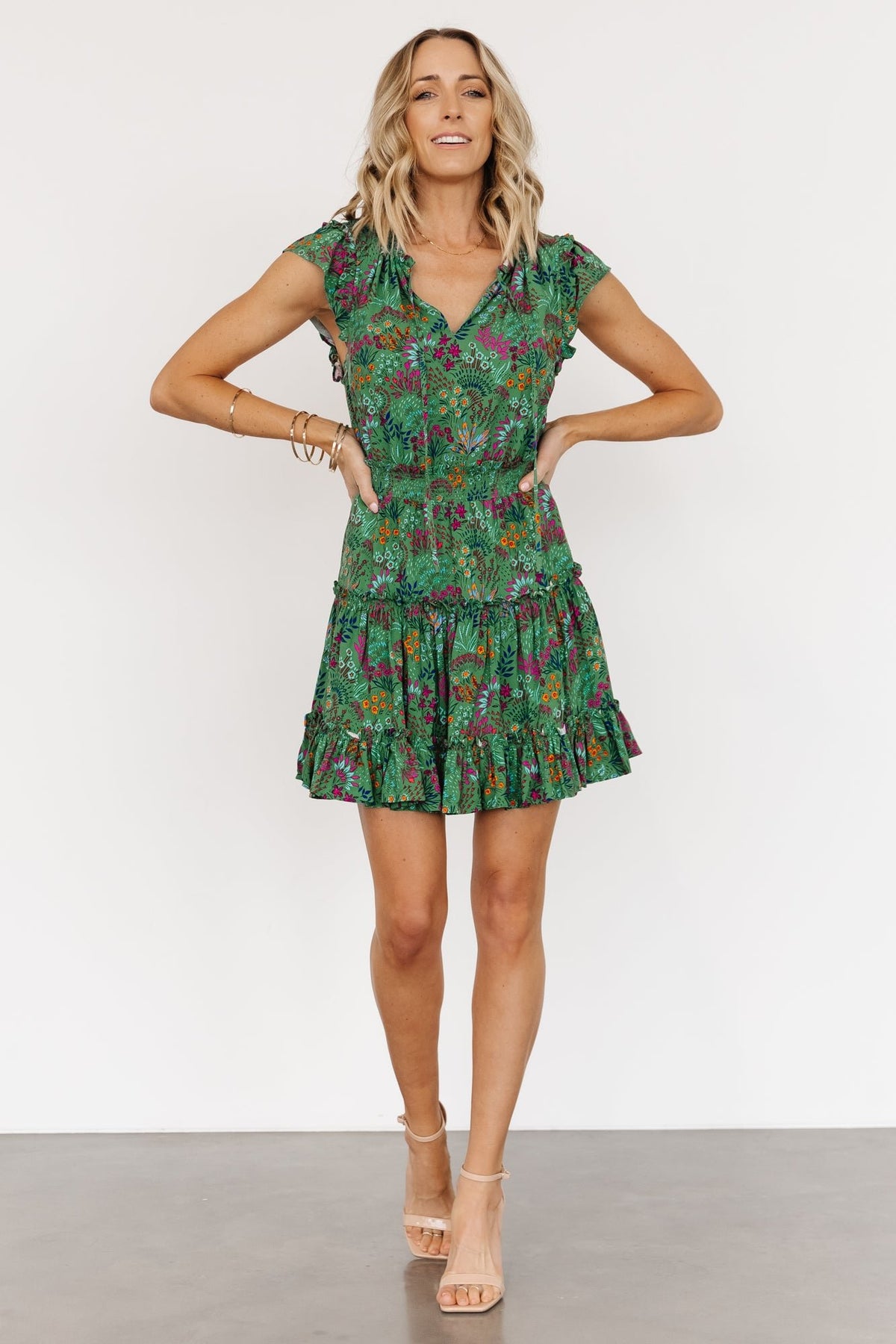 Close-up of the Rio Short Dress showing V-neck keyhole tie, ruffle detailing along the neckline, smocked elastic waist, and textured rayon fabric in green multi.