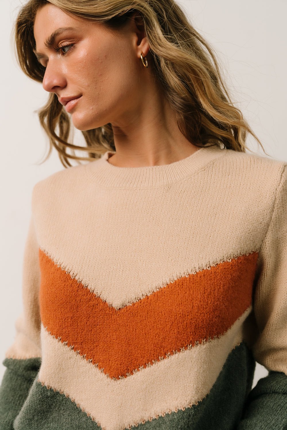 Model close-up wearing Rowen sweater, showing fit across the bust and shoulder with visible chevron color blocking.