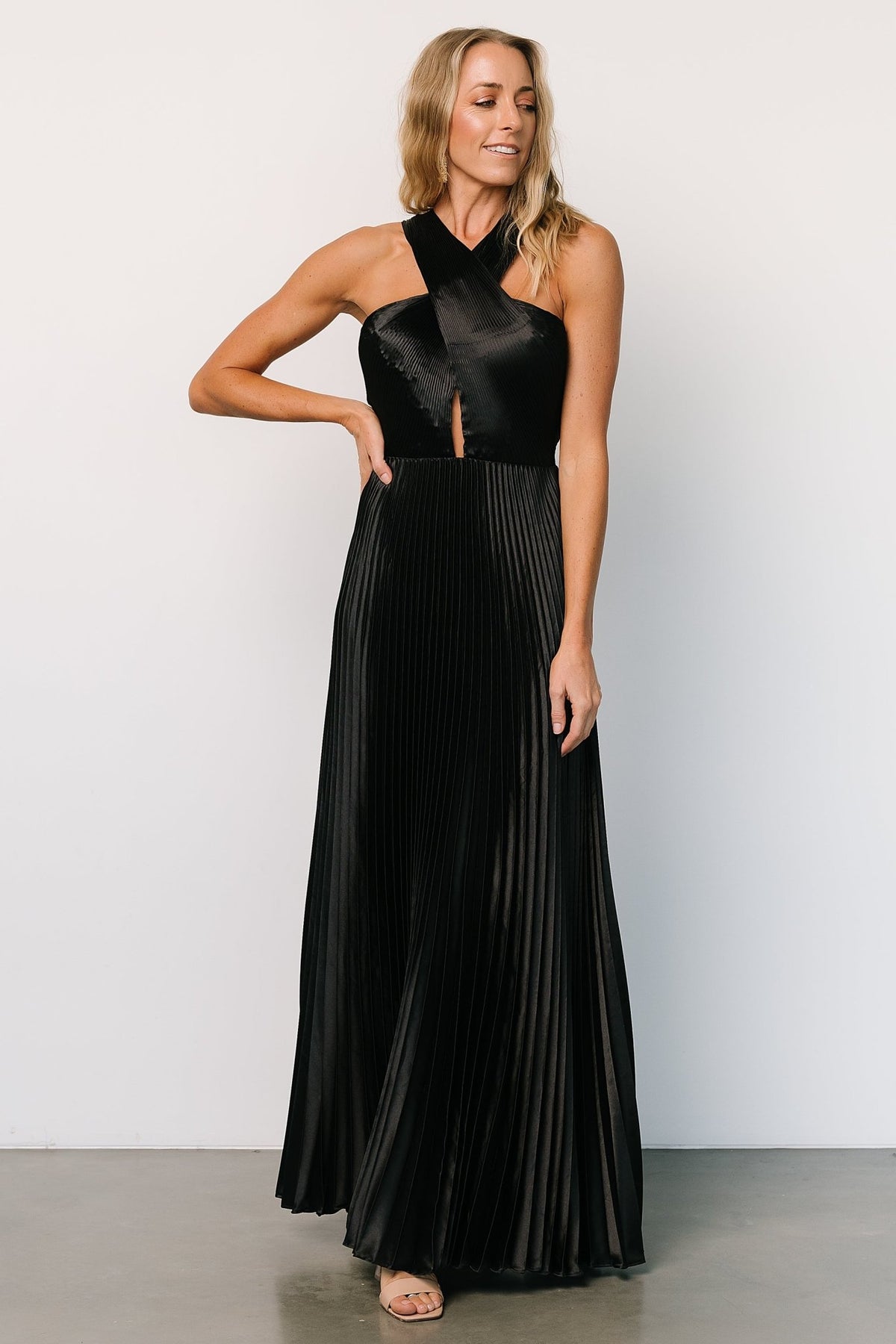 Movement shot of the Aakaa Sandra black halter maxi dress capturing the pleated skirt's flow and lightweight silhouette.