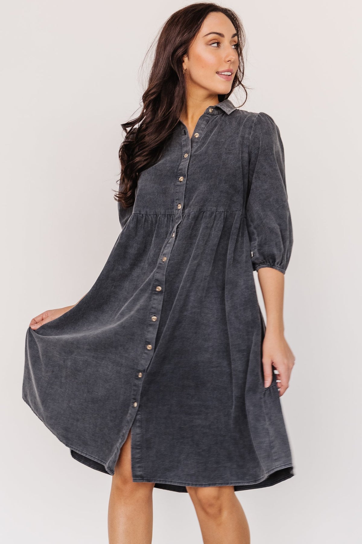 Three-quarter angle of washed black babydoll mini highlighting relaxed fit, tiered skirt, and soft cotton texture with subtle acid-wash details.