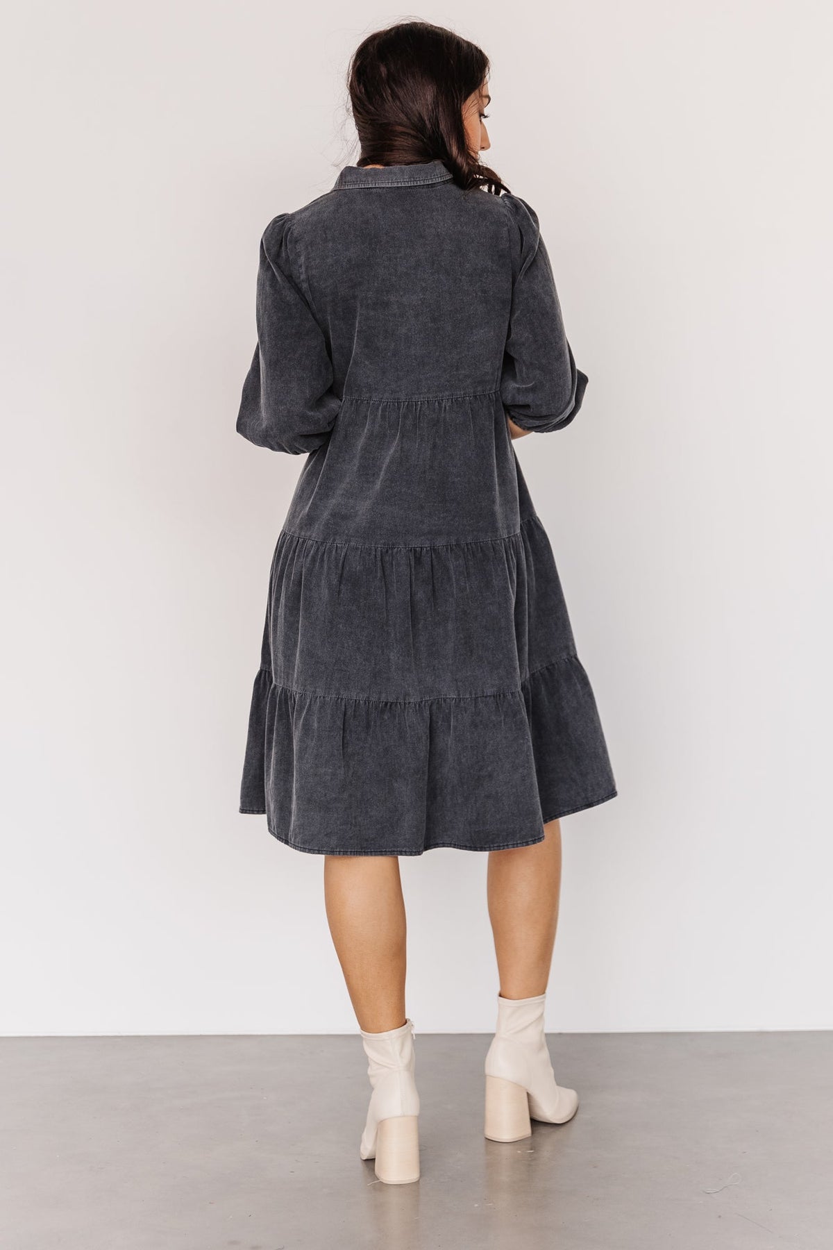 Styled flatlay of washed black babydoll mini emphasizing button-down front, side pockets, and tiered skirt for casual, travel-ready styling.
