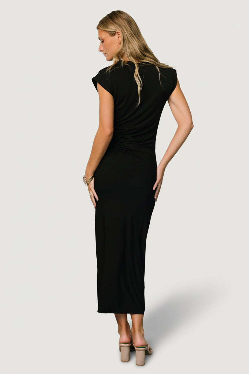 Detail shot of left leg slit and flowing skirt on Sasha ruched maxi dress in black, highlighting movement and clean finish.