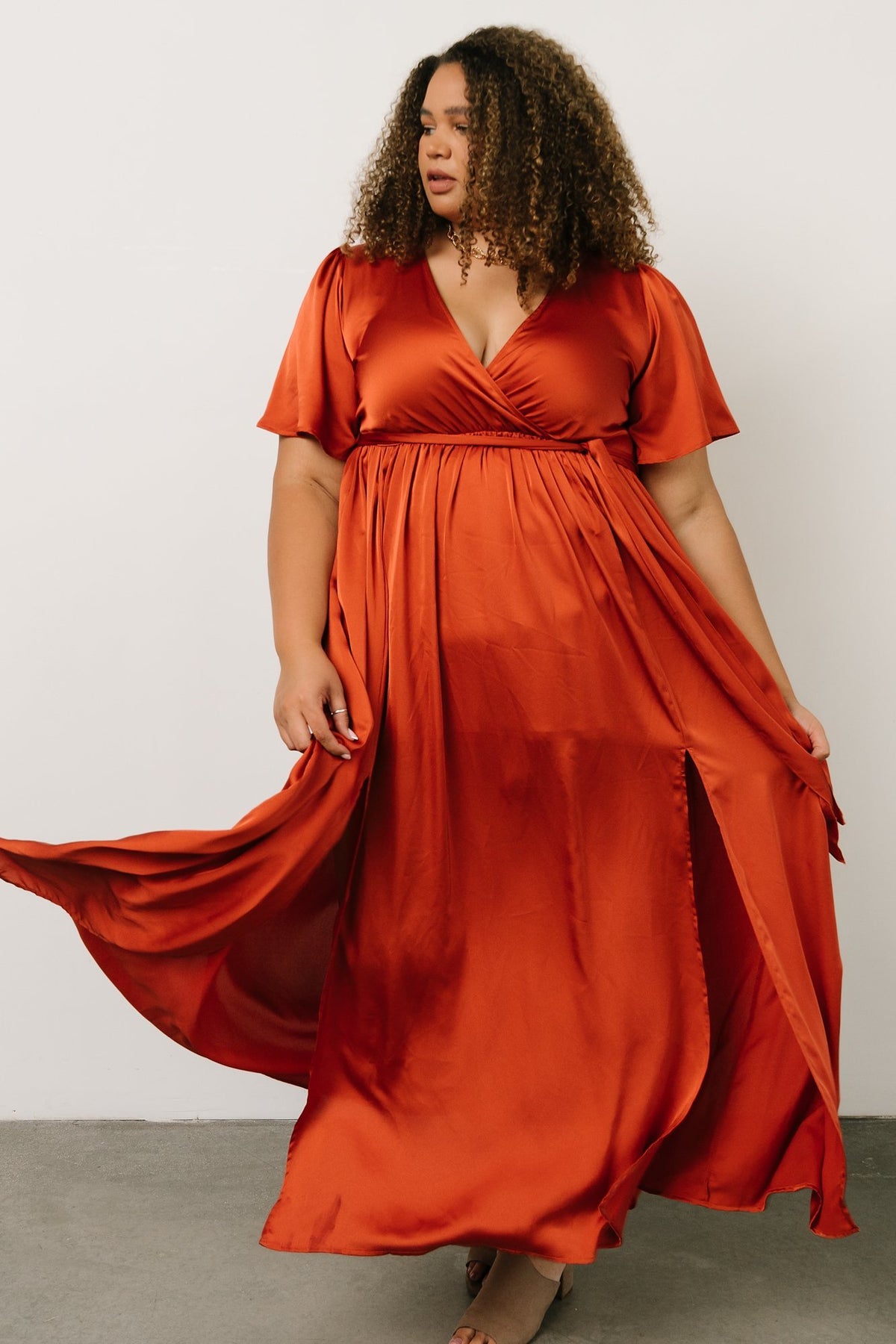 Close framing of the crossover bodice and V-neckline in rust satin-like fabric demonstrating modest coverage and feminine shape.