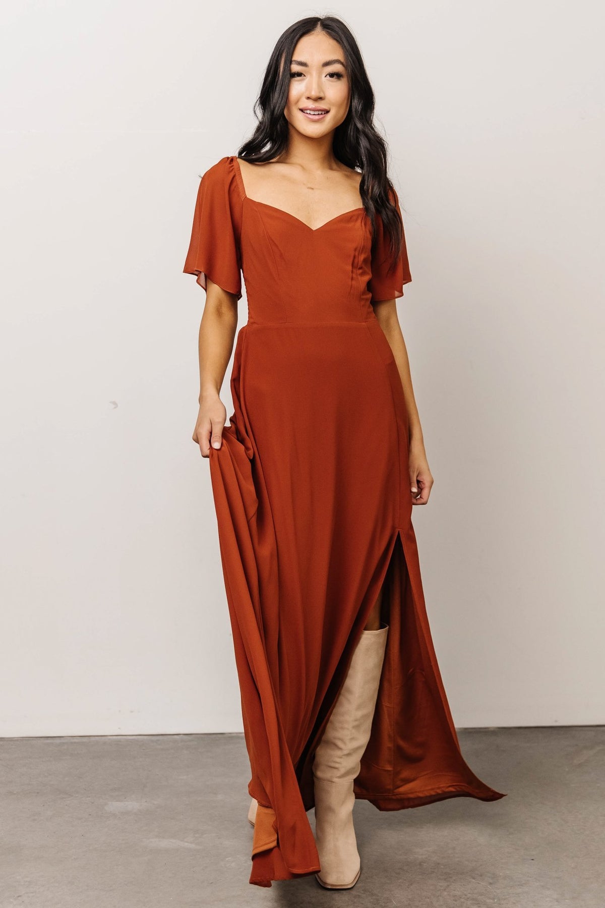 Model wearing Spice maxi dress showing side profile and front left slit, elastic shoulders and drape of lightweight chiffon fabric