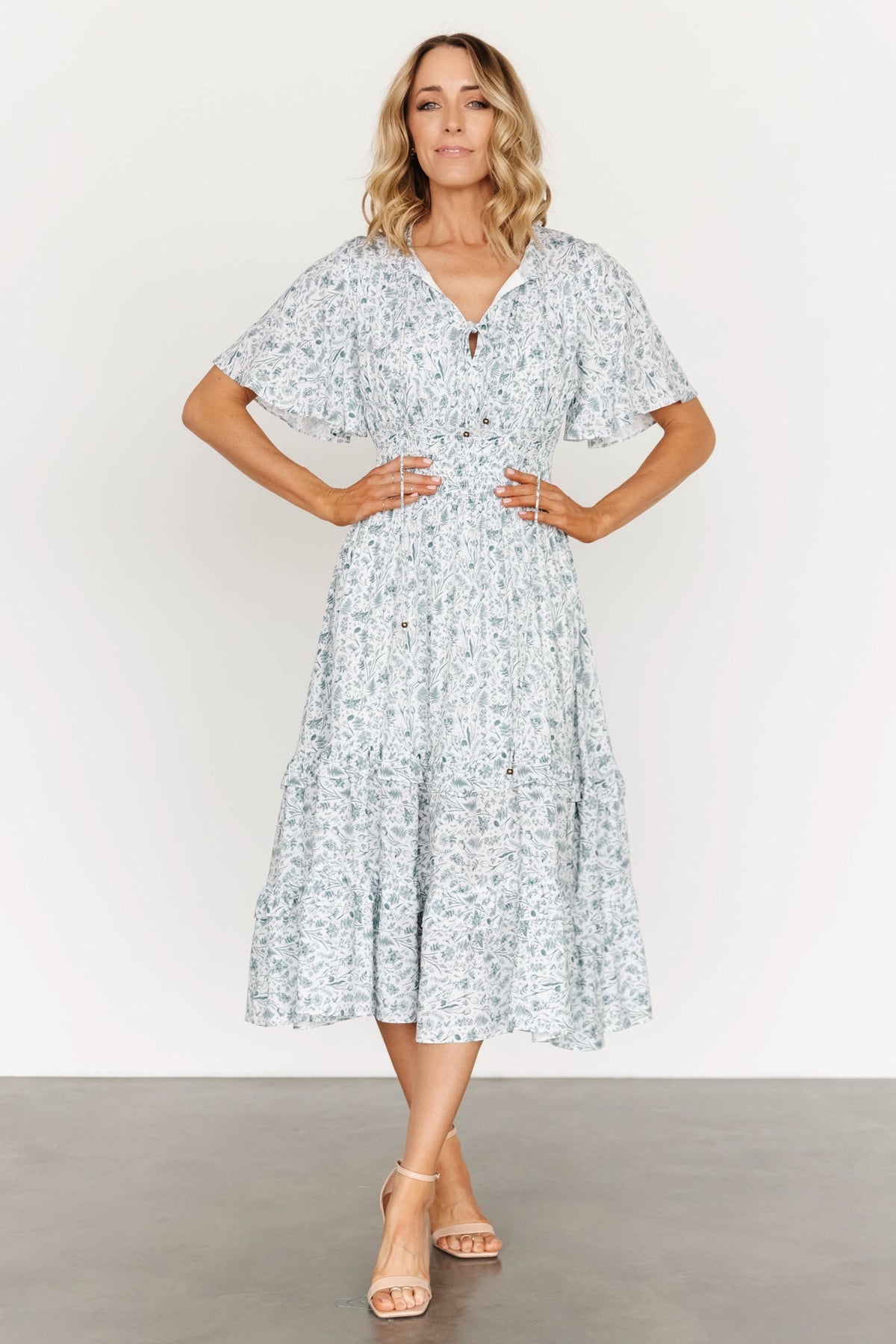 Side profile of white and sage boho midi dress showing short sleeves, gathered shoulder yoke, and flowing skirt movement.