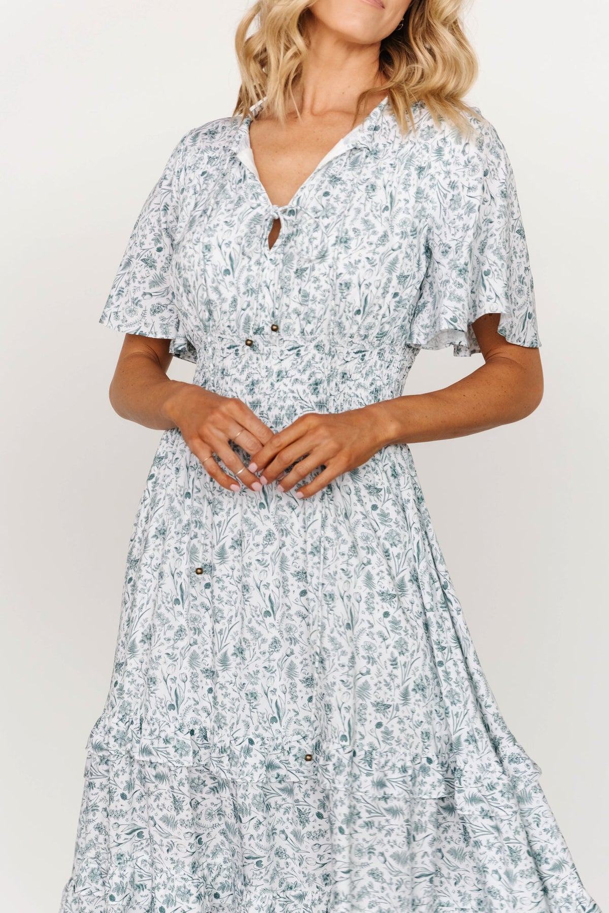 Close-up of bodice showing V-neckline, open seamed bodice, and adjustable bust and neckline ties in white and sage print.