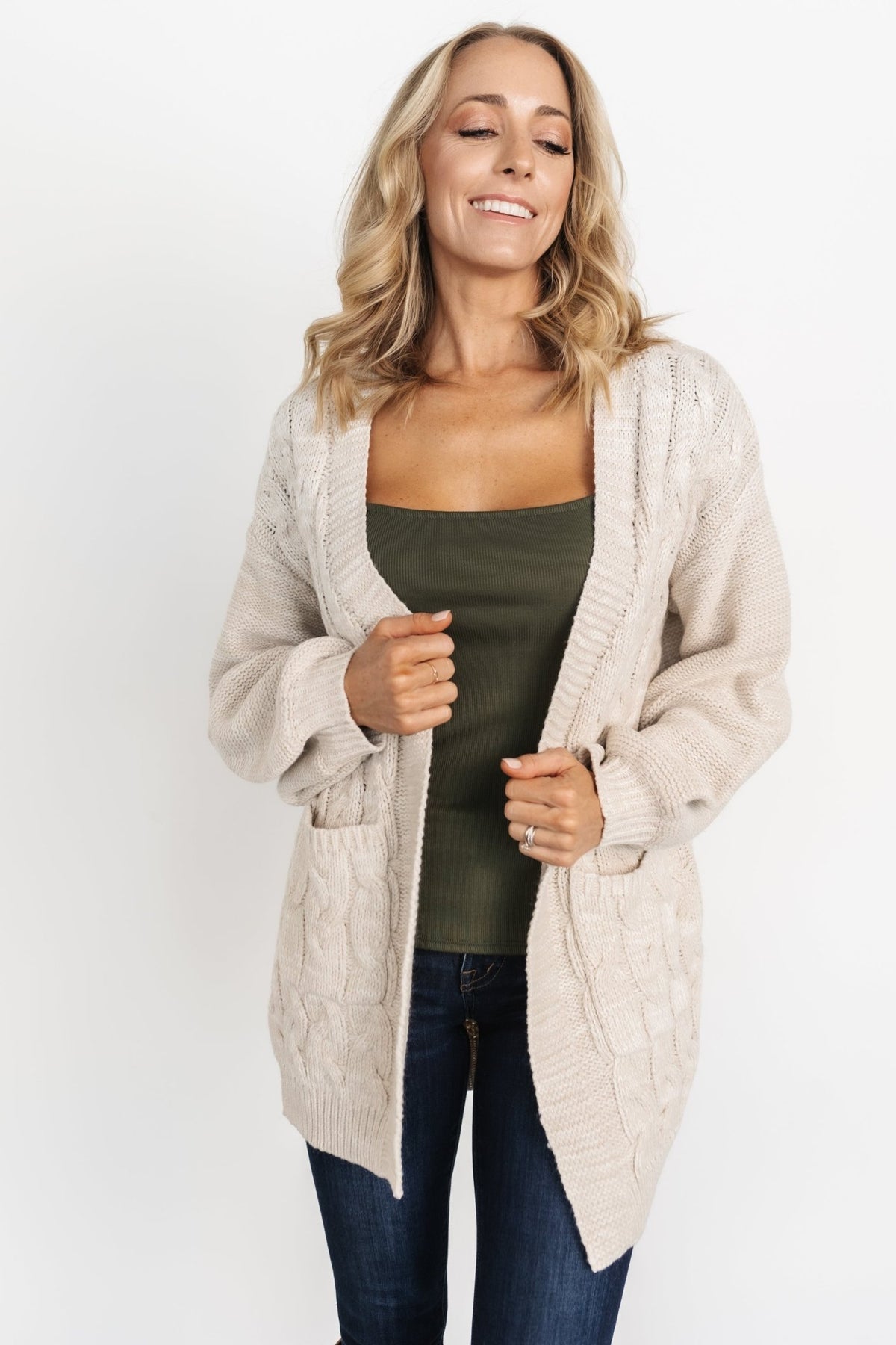 Close view of Spencer oatmeal cardigan showing chunky knit texture, ribbed neckline, and front patch pocket details on soft yarn.
