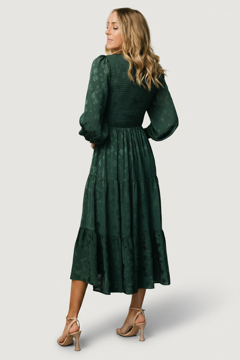 Full-length view of the Stockholm Smocked Dress in hunter green, displaying the tiered midi skirt, silhouette, and gentle movement.